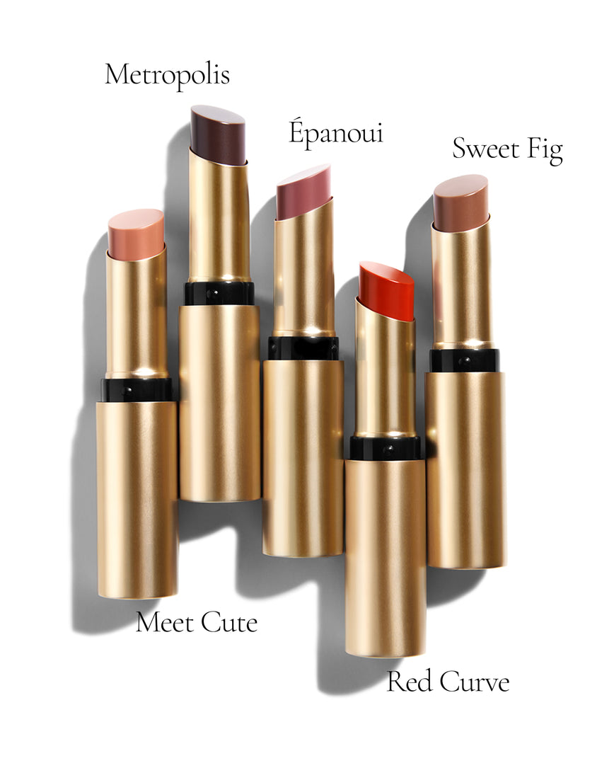 Display of full Baume Embrace Lip Colours - 5 different shades in their casing aligned horizontally and labelled: Meet Cute, Metropolis, Epanoui, Red Curve, Sweet Fig