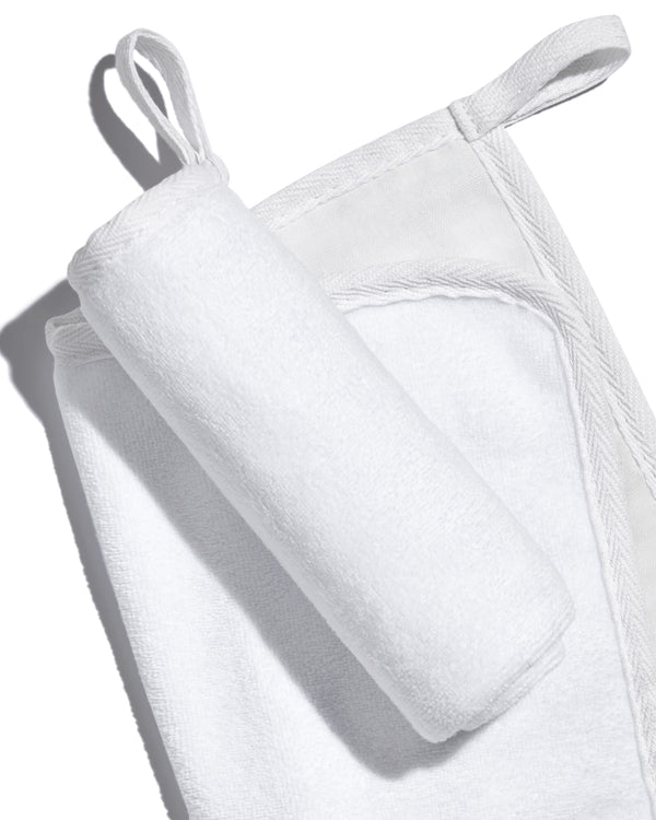 White, banded, Lisa Eldridge Luxuriously Gentle Cleansing & Exfoliating Cloth, one flat and one rolled up on top, showing different textures of the cloth faces and a loop for hanging up