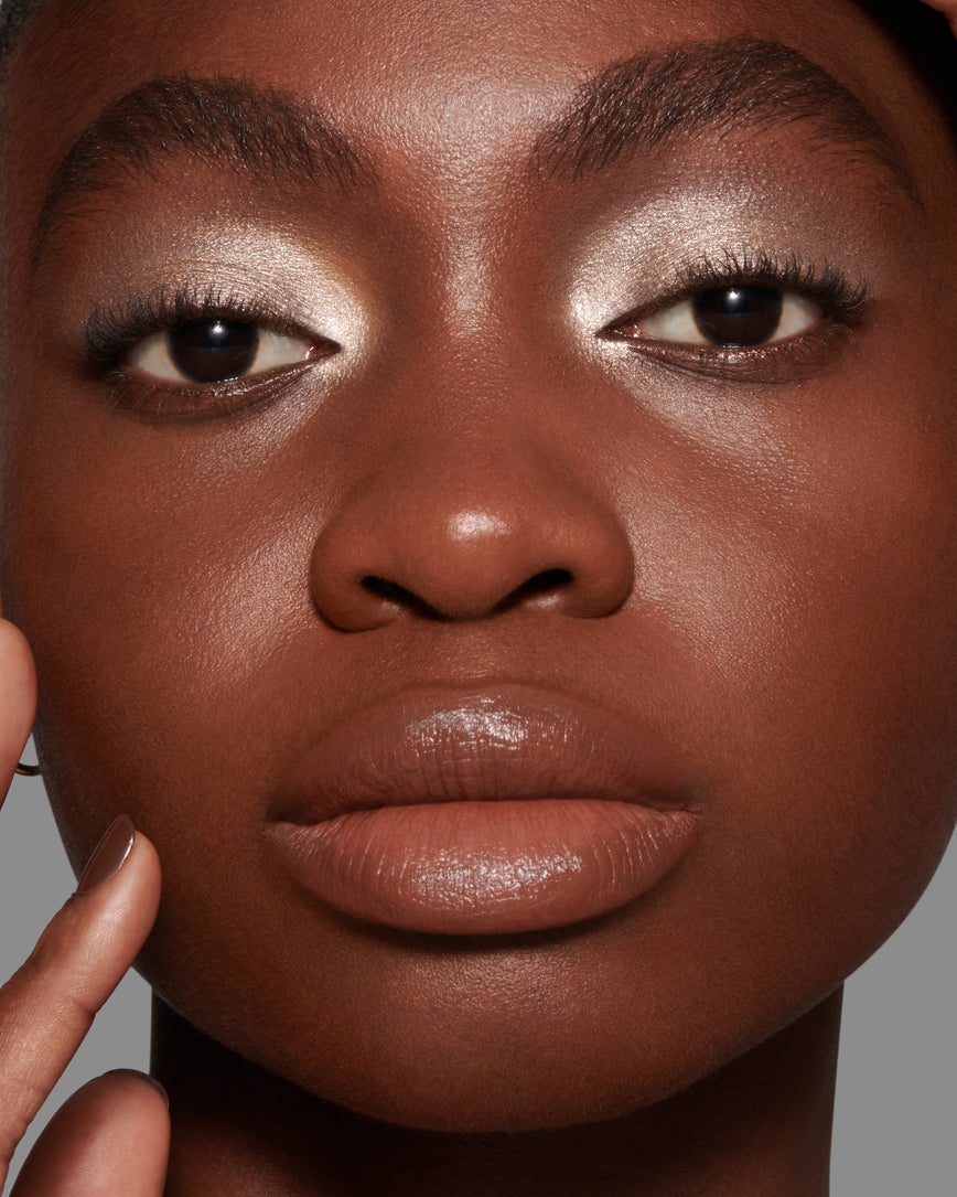 Close-up of a models face with a neutral background, wearing Cressida Liquid Lurex Liquid Eyeshadow