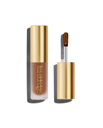 The end of a gold cap containing an applicator wand with a golden brown Liquid Silk eyeshadow on it, against a white background.