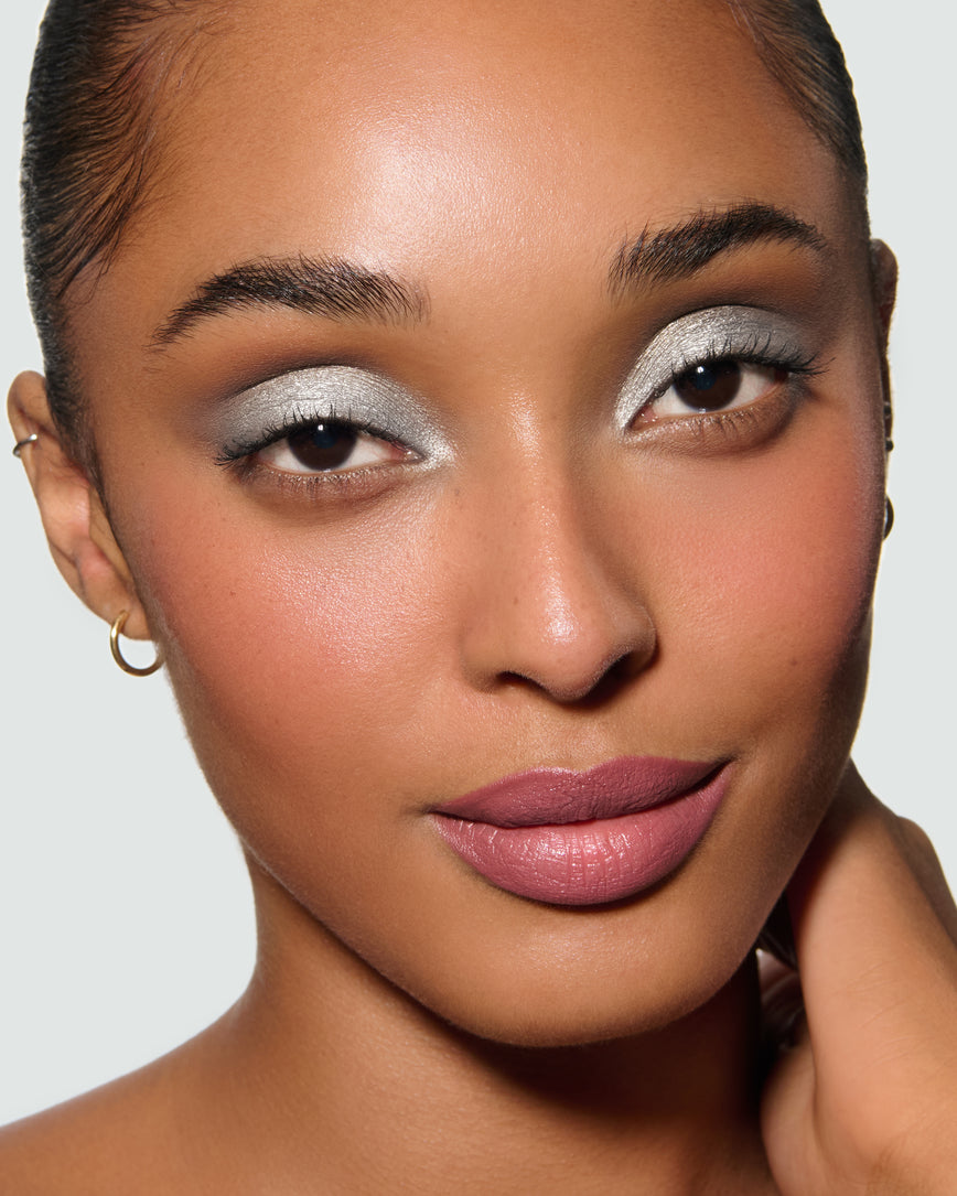 Close-up of a model's face, against a neutral background, wearing Aria Liquid Lurex Liquid Eyeshadow, a true, cool, clear silver.