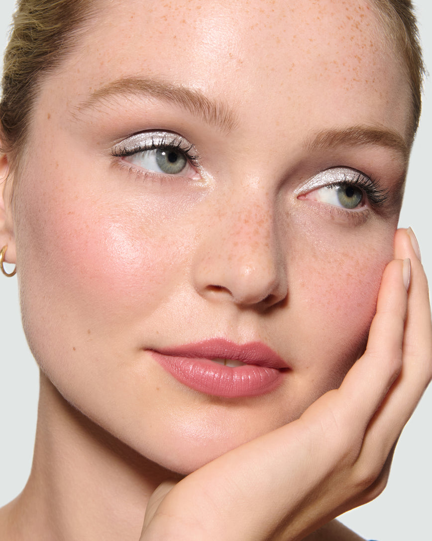 Close-up of a model's face, against a neutral background, wearing Aria Liquid Lurex Liquid Eyeshadow, a true, cool, clear silver.