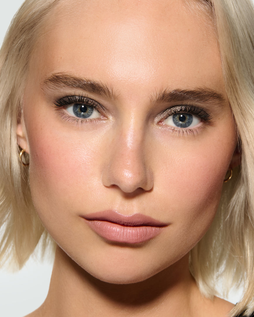 Close-up of a model's face against a neutral background, wearing Selene Liquid Lurex Liquid Eyeshadow, a tarnished, cool toned greenish/silver.