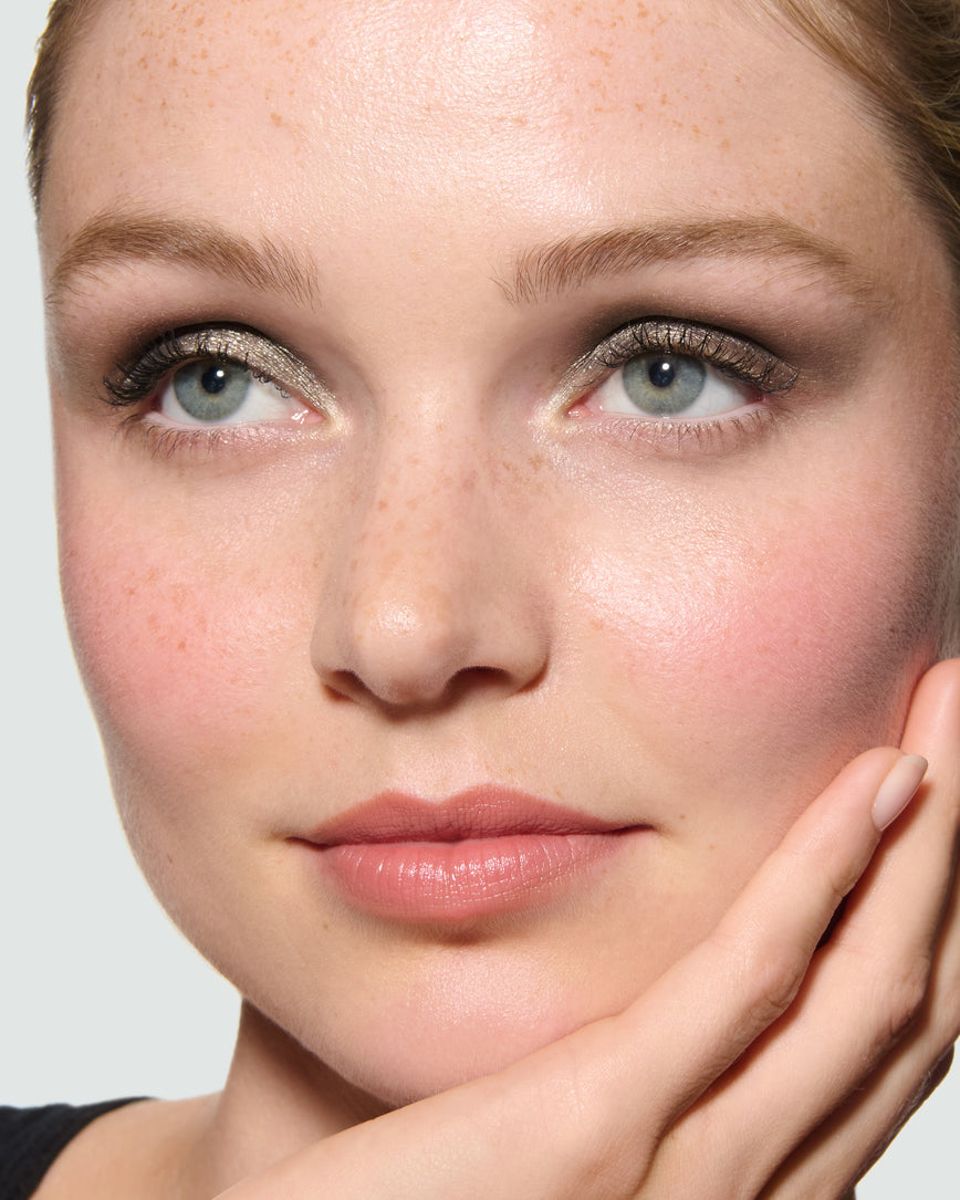 Close-up of a model's face against a neutral background, wearing Selene Liquid Lurex Liquid Eyeshadow, a tarnished, cool toned greenish/silver.