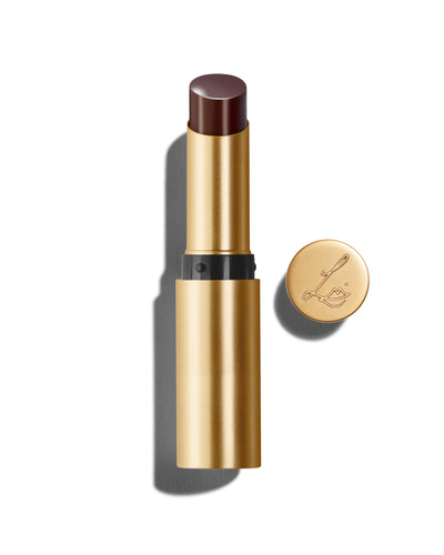 Baume Embrace in Metropolis, a deep blackberry lip colour with a gold-colored casing, next to the Lisa Eldridge logo-embossed lid