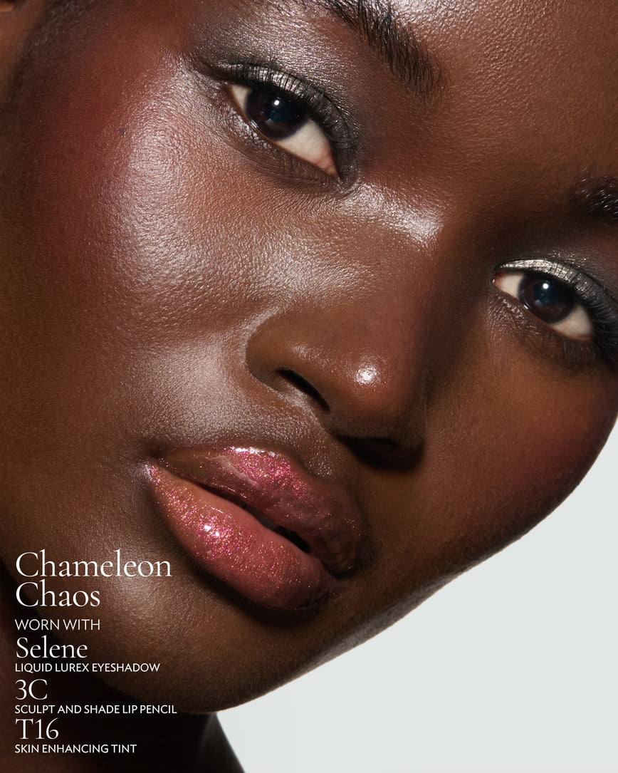 Close-up of a model's face against a neutral background, wearing Chameleon Chaos Gloss Embrace Sequin, with Selene Liquid Lurex, 3C Sculpt and Shade Pencil and T16 Skin Enhancing Tint.