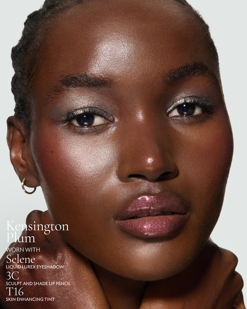 Close-up of a model's face against a neutral background, wearing Kensington Plum Gloss Embrace Sequin, with Selene Liquid Lurex, 3C Sculpt and Shade Pencil, and T16 Skin Enhancing Tint.