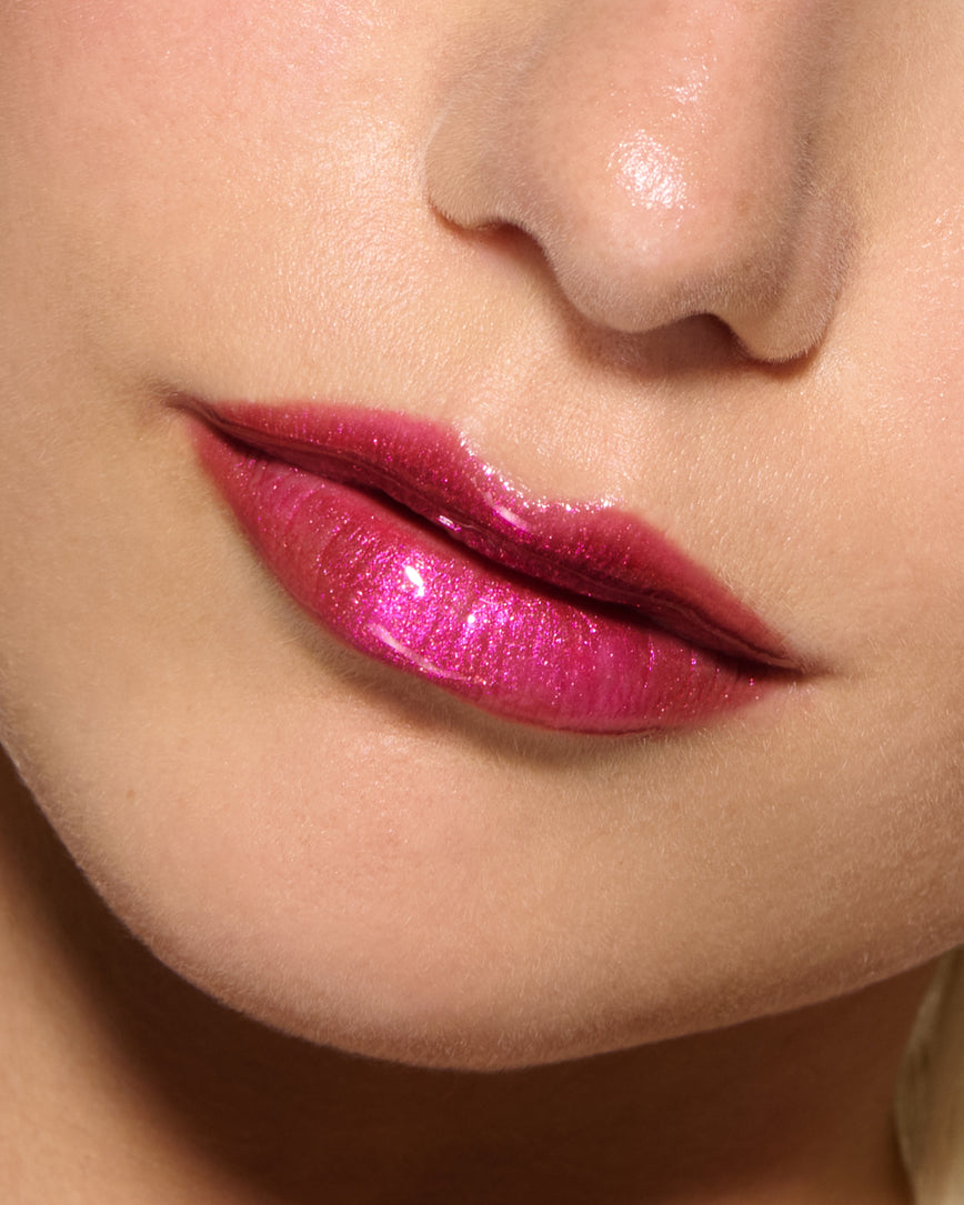 Close-up of a model's lips against a neutral background, wearing Peek-A-Boo Pink Gloss Embrace Sequin, chocolatey plum berry with golden sparkle.