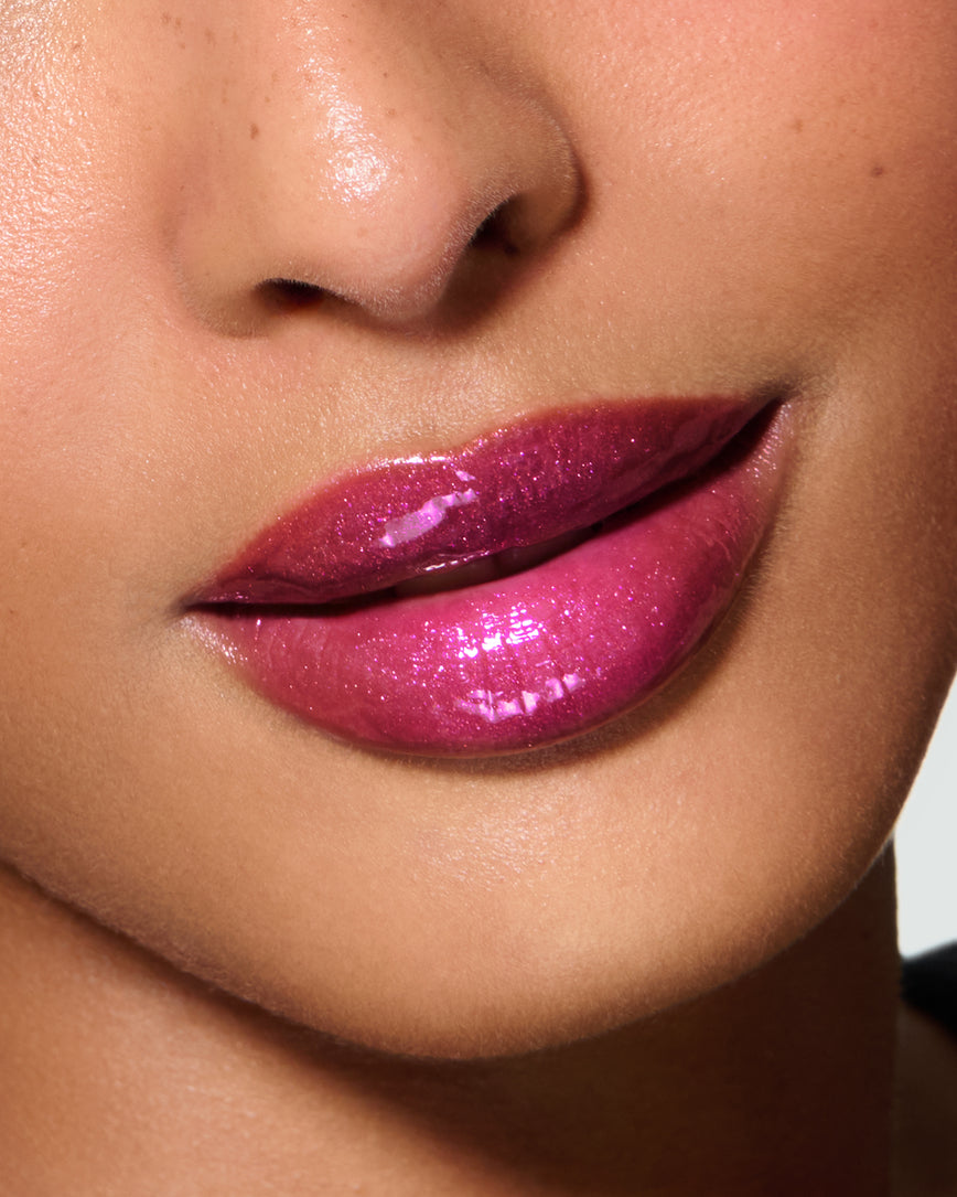 Close-up of a model's lips against a neutral background, wearing Peek-A-Boo Pink Gloss Embrace Sequin, chocolatey plum berry with golden sparkle.