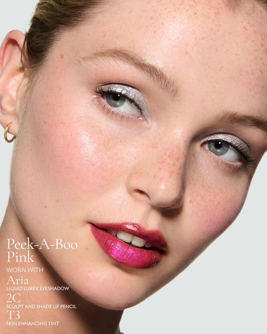 Close-up of a model's face against a neutral background, wearing Peek-A-Boo Pink Gloss Embrace Sequin, with Aria Liquid Lurex, 2C Schulp and Shade Pencil, and T3 Skin Enhancing Tint.