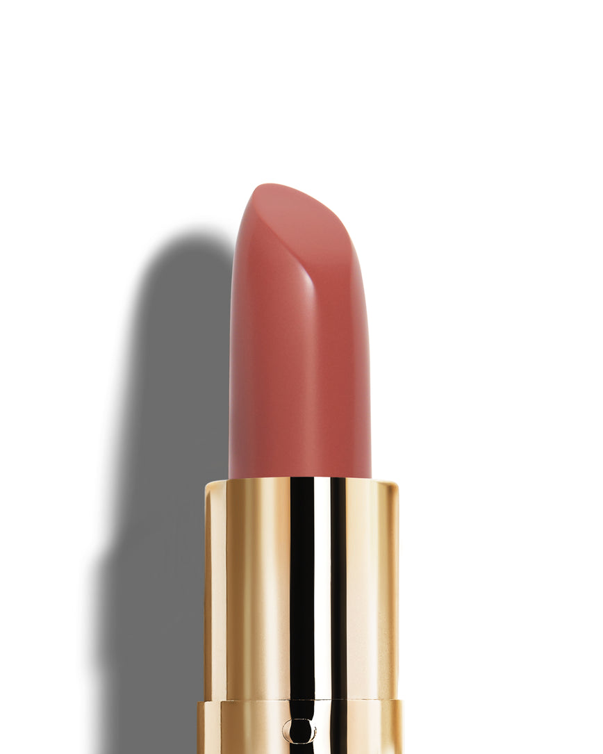 Neutral pink lipstick with gold casing on a white background