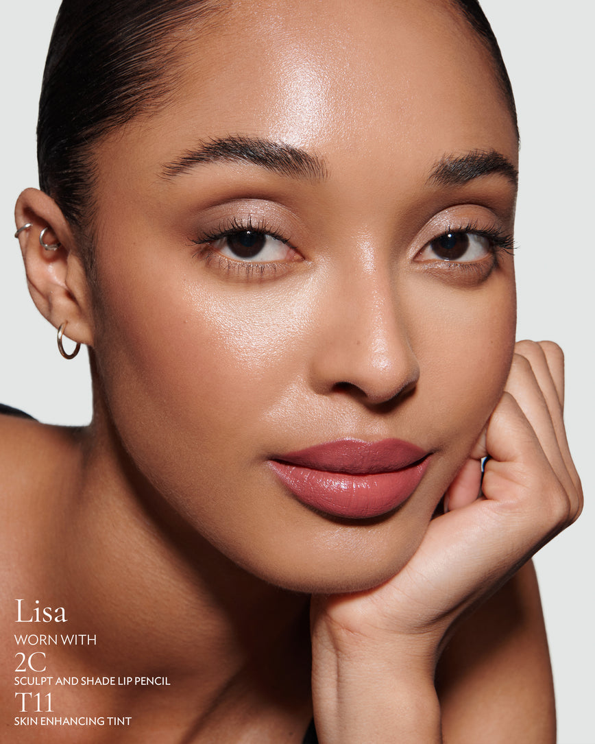 Close-up of a woman with a grey background, focusing on the lip colour - neutral pink Lisa, with notes on the 2C Sculpt and Shade Pencil and T11 Skin Enhancing Tint