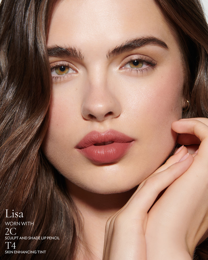 Close-up of a woman with a grey background, focusing on the lip colour - neutral pink Lisa, with notes on the 2C Sculpt and Shade Pencil and T4 Skin Enhancing Tint