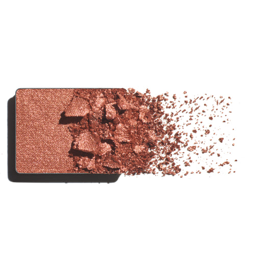 Makeup eyeshadow refill with warm copper powder on a white background