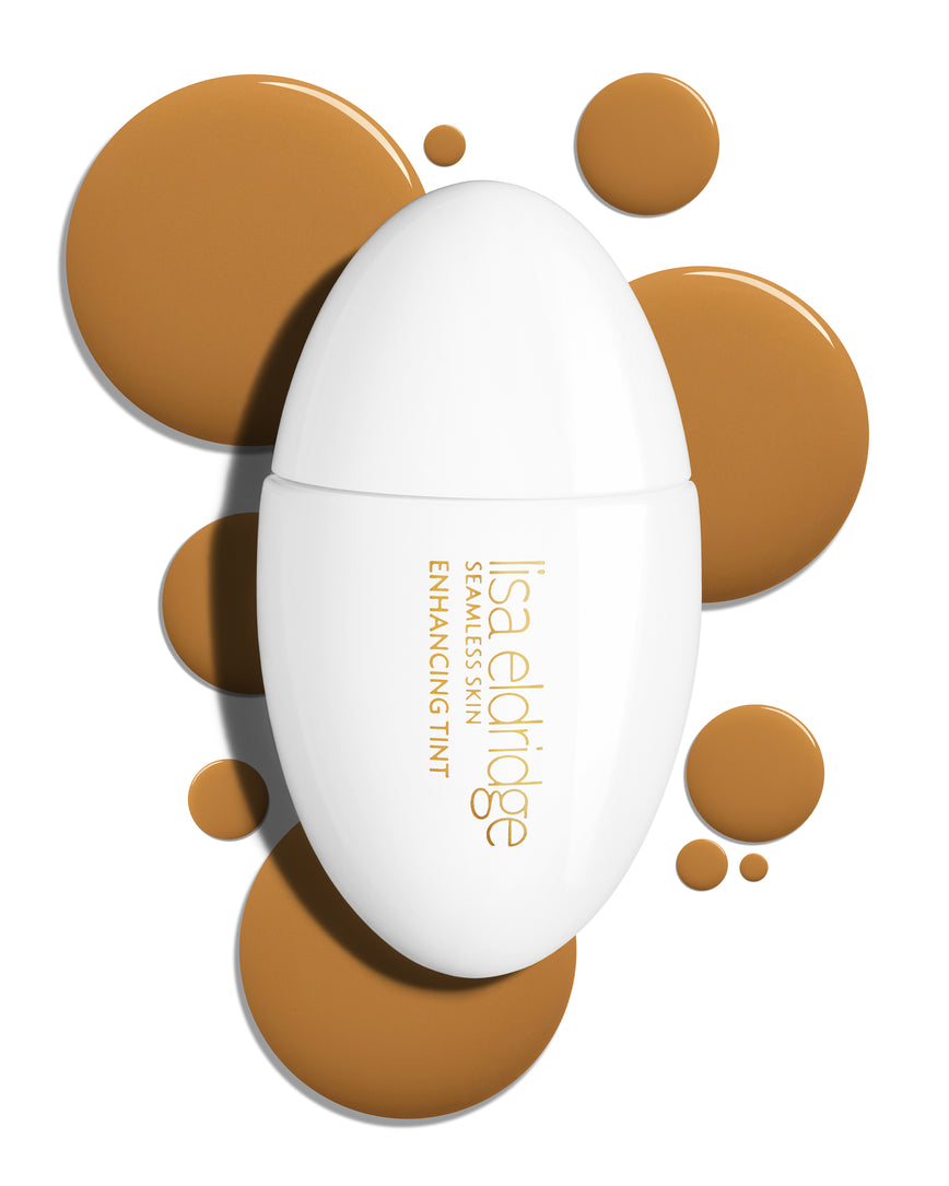 The white pod packaging of Seamless Skin Enhancing Tint by Lisa Eldridge with drops of T11 in the background