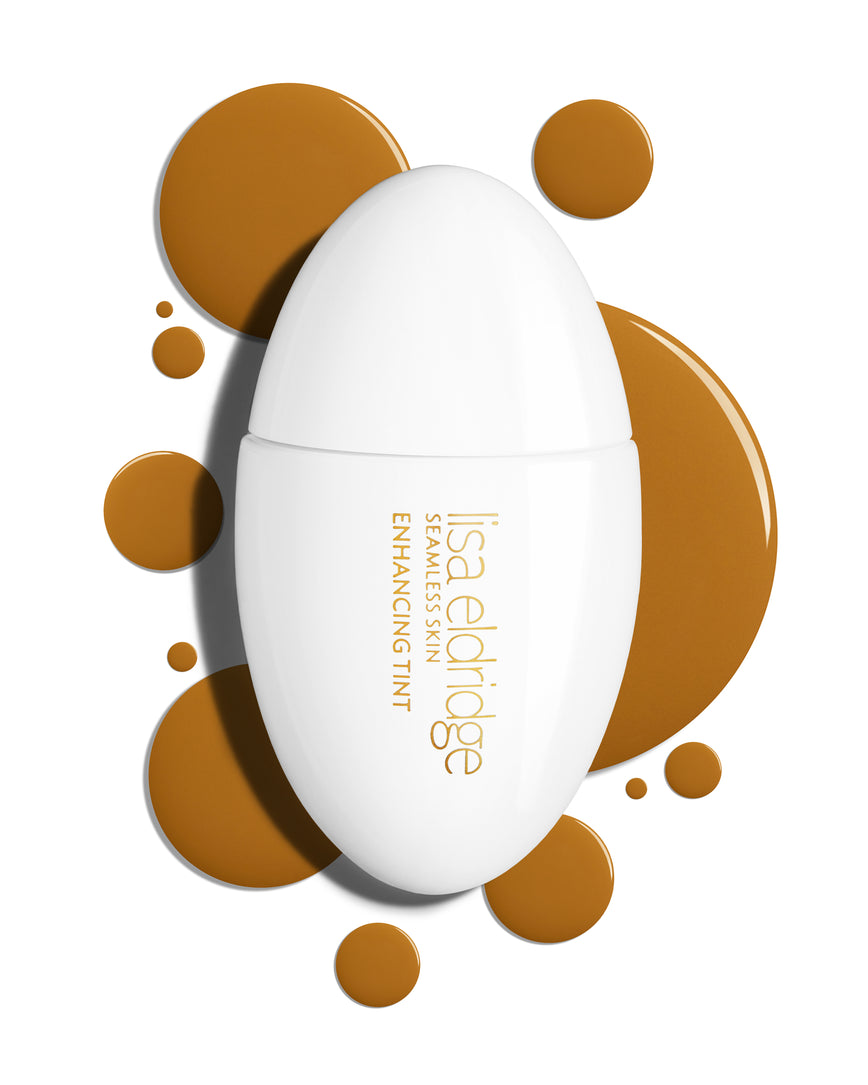 The white pod packaging of Seamless Skin Enhancing Tint by Lisa Eldridge with drops of T13 in the background
