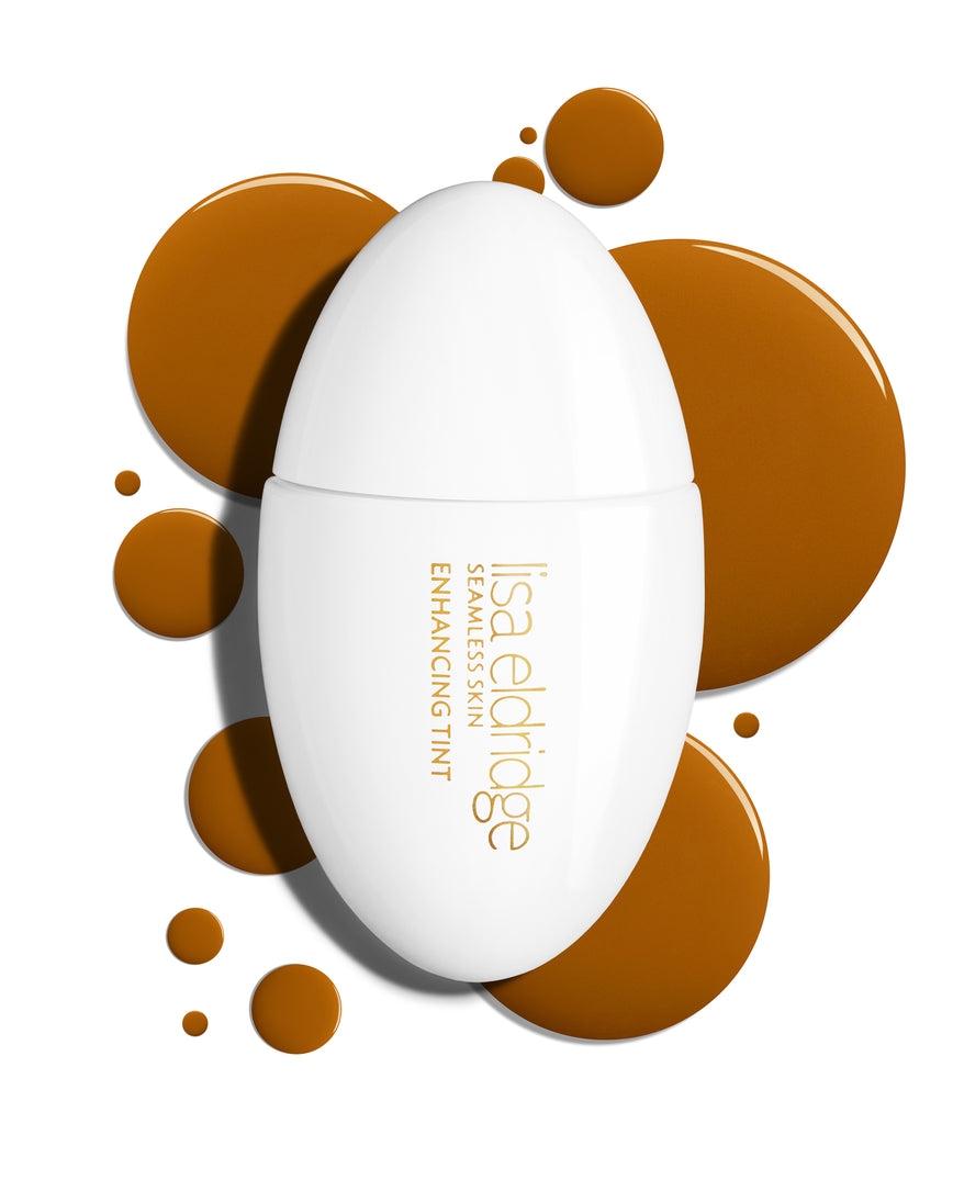 The white pod packaging of Seamless Skin Enhancing Tint by Lisa Eldridge with drops of T14 in the background