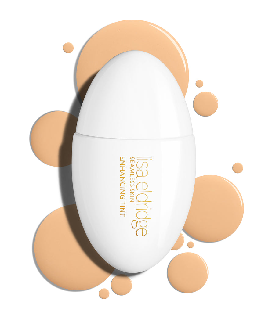 The white pod packaging of Seamless Skin Enhancing Tint by Lisa Eldridge with drops of T3 in the background