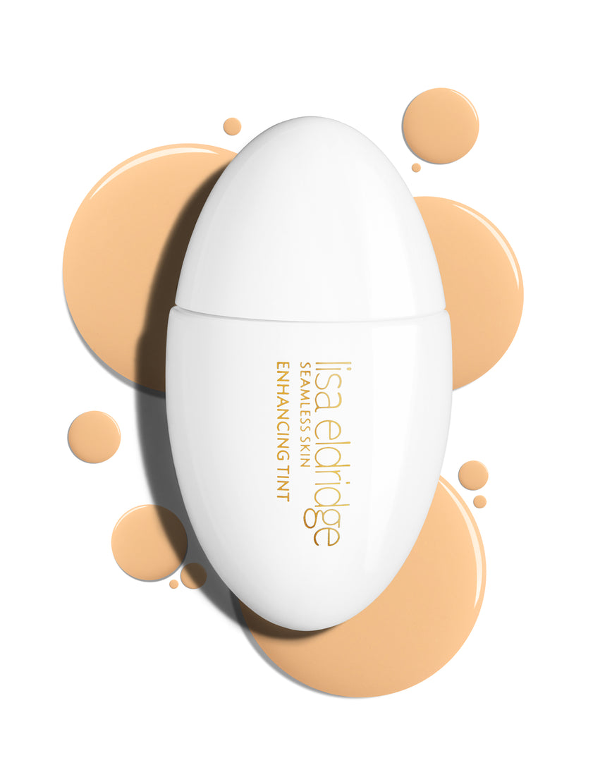 The white pod packaging of Seamless Skin Enhancing Tint by Lisa Eldridge with drops of T4 in the background