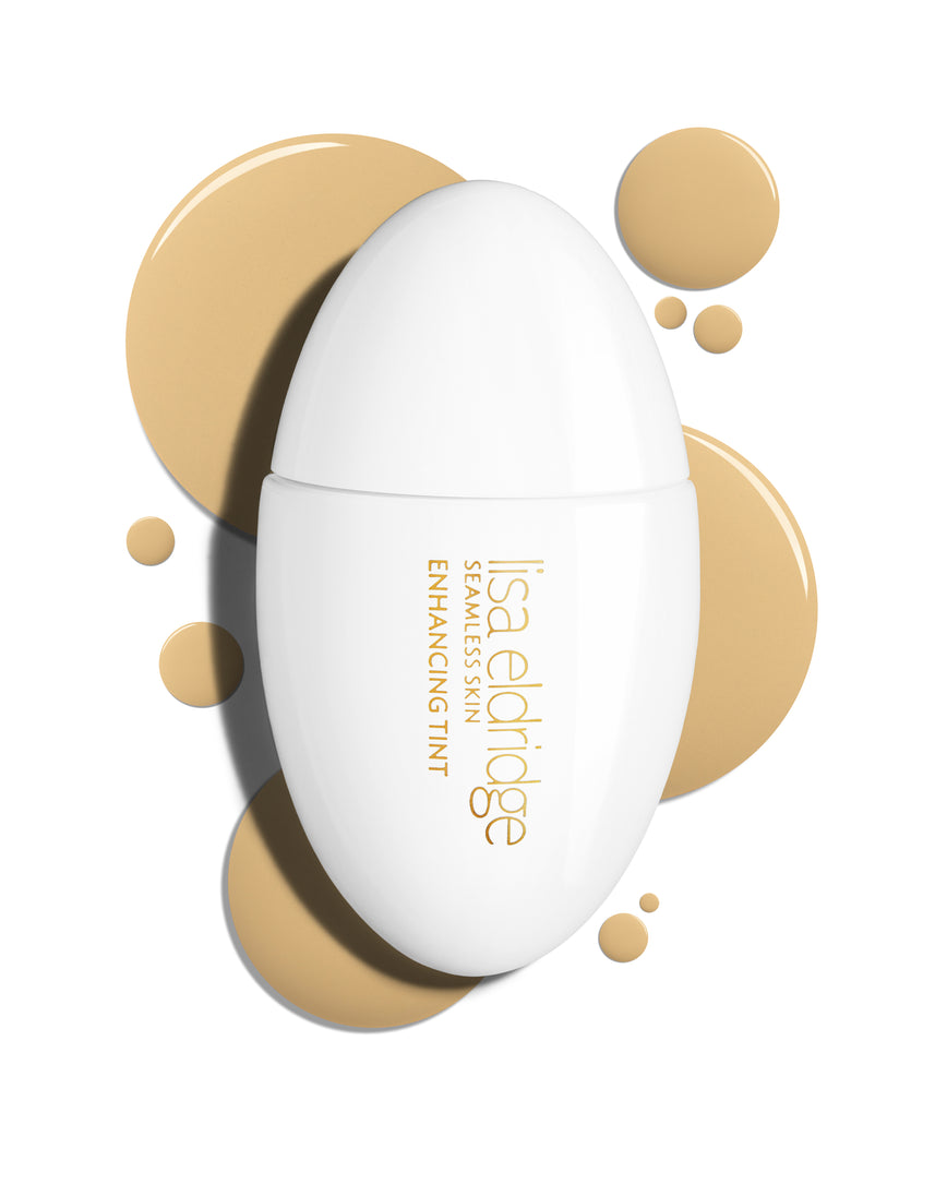 The white pod packaging of Seamless Skin Enhancing Tint by Lisa Eldridge with drops of T5 in the background
